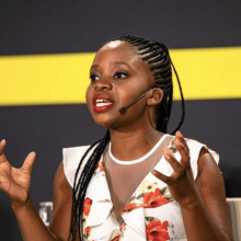 A young woman articulating while speaking at the podium during the Young Activists summit. 